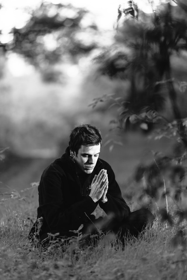 grayscale-photography-of-man-sitting-on-grass-field-156151