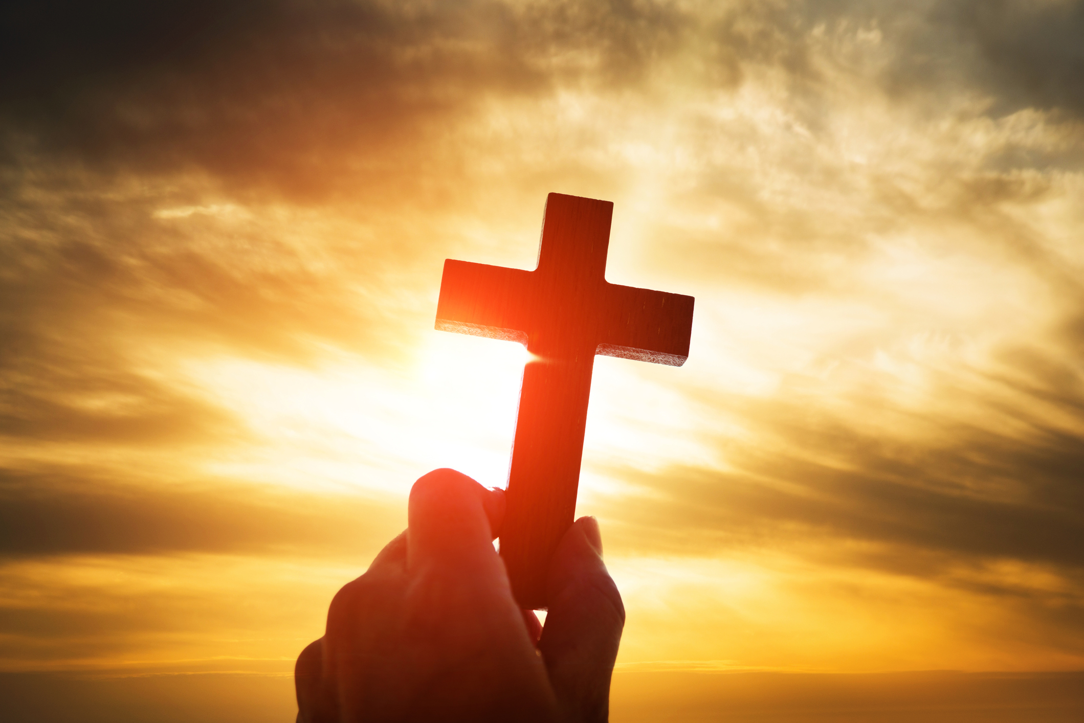 Human hand holding wooden cross